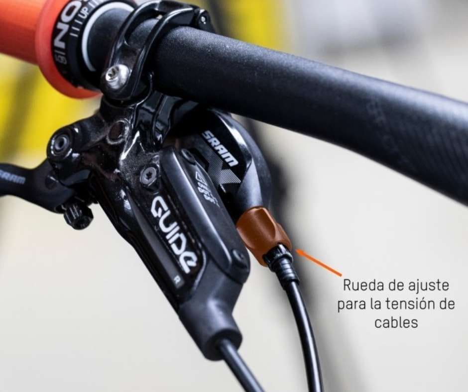 Mecánico ajustando la tensión del cable de cambio mediante el tensor de barril (barrel adjuster), realizando la indexación fina para sincronizar el desviador con los piñones.