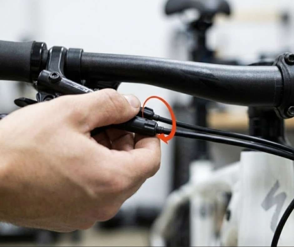 Ciclista realizando un ajuste fino de la transmisión mediante el tensor en línea ubicado en la funda del cable de cambio, corrigiendo la tensión para mejorar la indexación de las marchas.