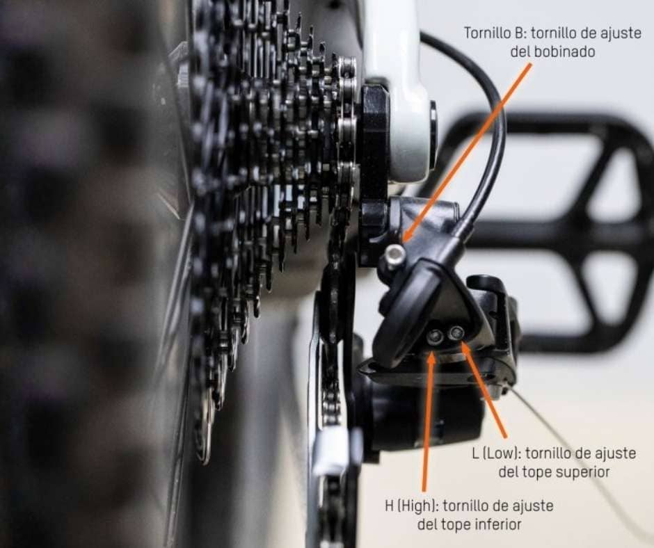 Esquema gráfico de un cambio trasero indicando con flechas la ubicación y función de los tornillos de regulación: H (High/Tope inferior) para el piñón pequeño y L (Low/Tope superior) para el piñón grande.